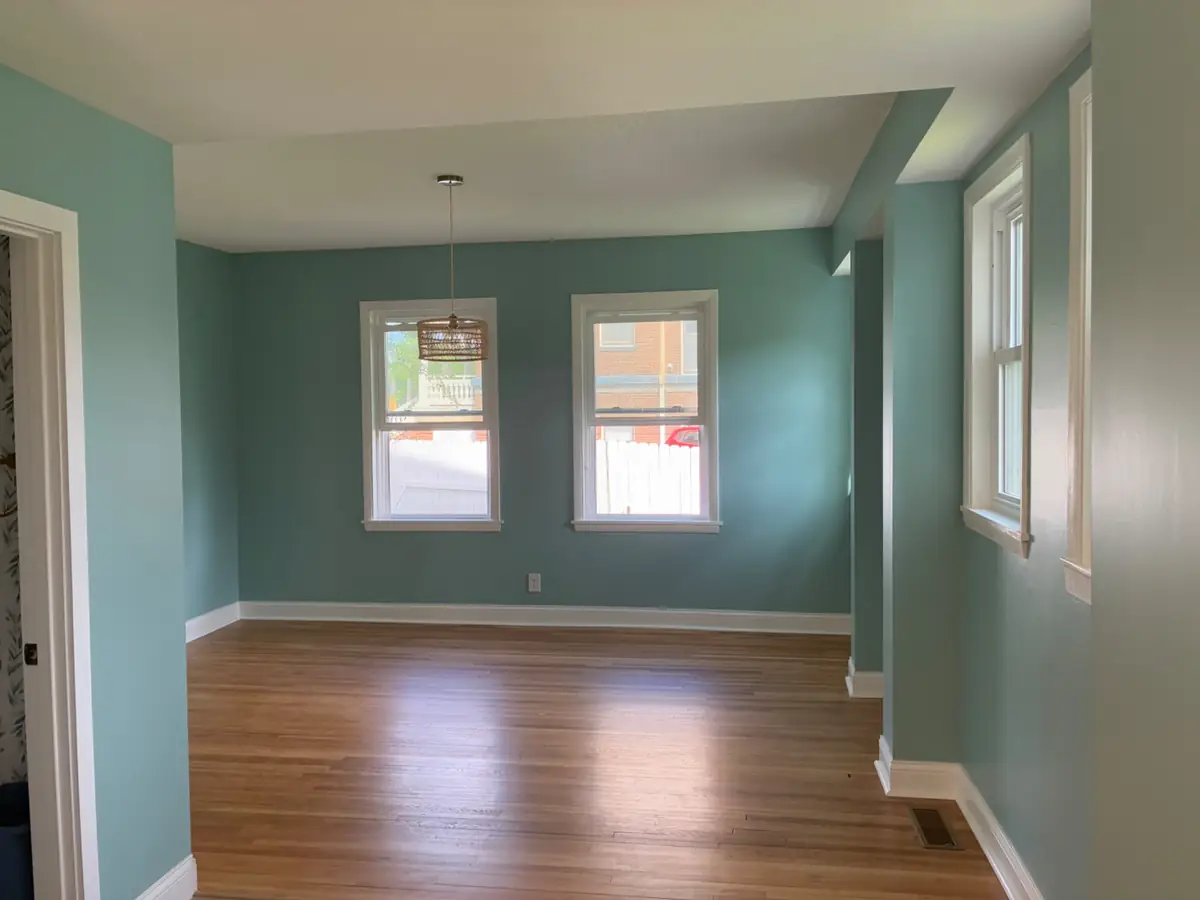 Dining room repainted in deep teal with white trim by Pro Painting Jr